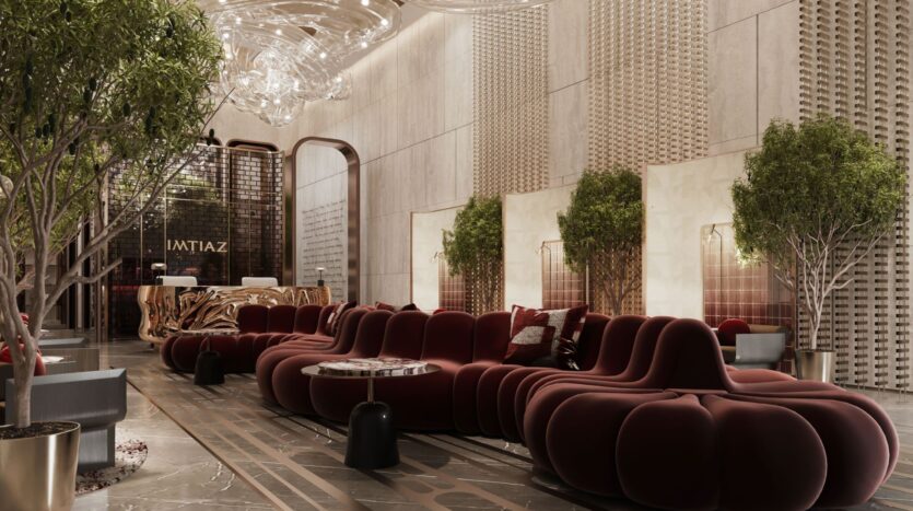 The hotel's luxurious lobby, dubbed The Symphony, features modern curved burgundy sofas, small round tables, large potted green trees, an elegant gilded reception desk and elegant chandeliers suspended from a high textured ceiling.