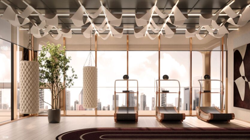 A modern gym with large windows overlooking the city skyline, The Symphony features two white punching bags, three wooden treadmills, a potted tree and abstract decorations on the ceiling and walls.