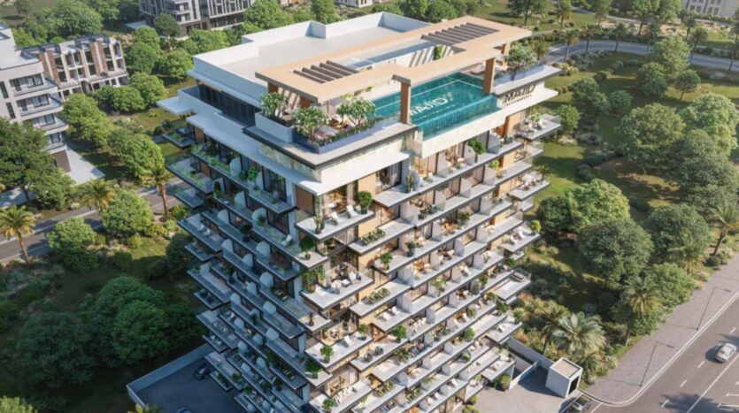 Aerial view of Arlington Park 2, a modern multi-story residential building with large balconies, a rooftop swimming pool, lush vegetation, and surrounded by trees, roads, and neighboring buildings.