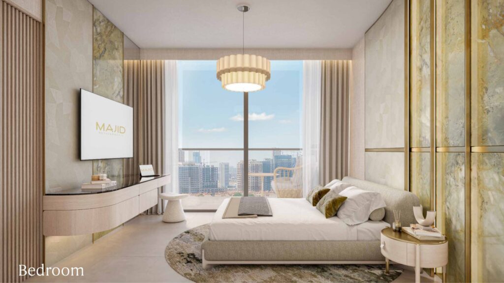 Modern bedroom in Arlington Park 2 with a large window offering a view of the city, a double bed with neutral bedding, a round rug, a wall-mounted television, a contemporary chandelier, and elegant décor in shades of beige, gold, and cream. The "Bedroom" label is located in the corner.