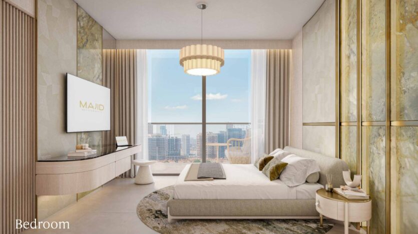 Modern bedroom in Arlington Park 2 with a large window offering a view of the city, a double bed with neutral bedding, a round rug, a wall-mounted television, a contemporary chandelier, and elegant décor in shades of beige, gold, and cream. The "Bedroom" label is located in the corner.