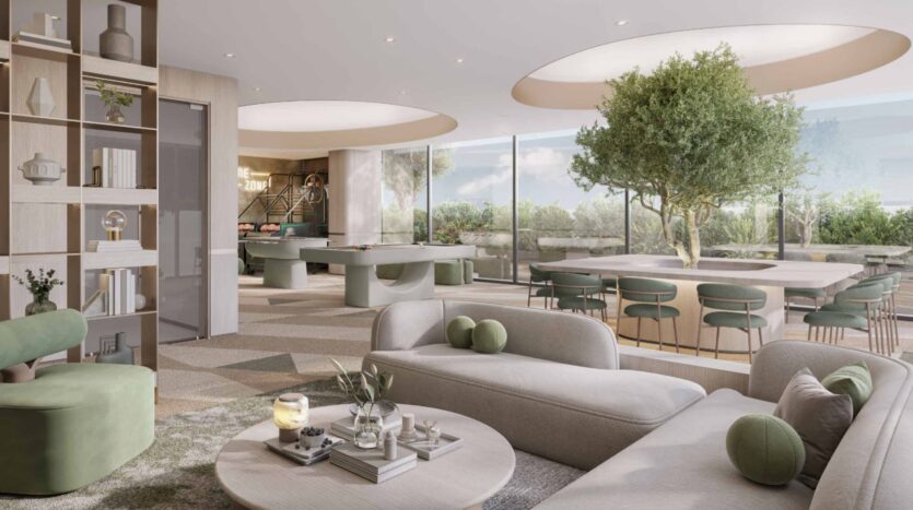 Modern lounge with light, neutral furniture, touches of green, and round tables. The large windows and skylights at Arlington Park 2 illuminate the trees and indoor plants, creating a bright, airy atmosphere inspired by nature.