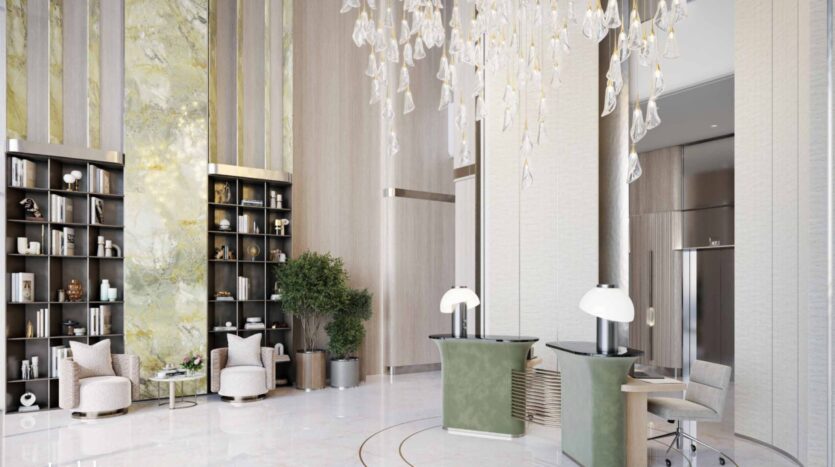 The luxurious and modern lobby of Arlington Park 2 features high ceilings, a large chandelier, elegant green and beige seating, tall shelves, indoor plants, and marble flooring. Light floods in, highlighting the sophisticated decor.