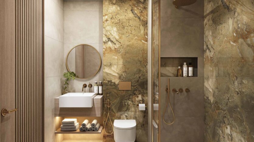 Modern bathroom in Arlington Park 2 with gold, beige, and brown marble walls, a floating sink under a round mirror, an open shelf for towels, a toilet, and a shower with gold fixtures and toiletries on a built-in shelf.
