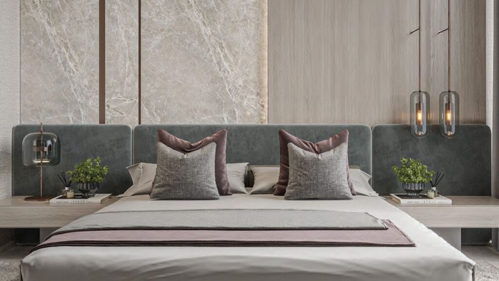 Camera da letto moderna con un grande letto dotato di cuscini grigi e malva, una morbida testiera grigia e comodini sormontati da piante in vaso, libri e lampade a sospensione, che creano un'atmosfera serena Floarea Breeze su pareti strutturate in tonalità chiare.