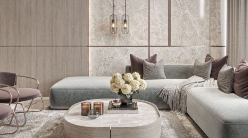 Salotto moderno con divano componibile grigio chiaro, accenti murali in marmo e tappeto Floarea Breeze. Un tavolino rotondo in marmo ospita fiori e libri, mentre morbide coperte, candele e lampade a sospensione contemporanee completano il look.