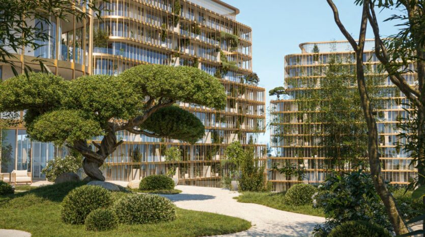 Modern Hado buildings with curved glass facades and wooden details are surrounded by lush greenery, featuring a sculpted tree, vibrant bushes, and landscaped paths under a clear blue sky.