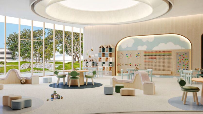 A spacious, modern playroom with large windows, child-sized furniture, toys, and Hado activity stations. The room features playful décor, pastel colors, and cloud-themed wall art for a bright and welcoming atmosphere.