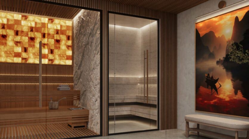 Modern spa room with a wooden sauna on the left, a glass-enclosed hado-inspired steam room in the center, and a bench beneath a large wall mural depicting a tranquil river at sunset on the right. Warm ambient lighting throughout the room.