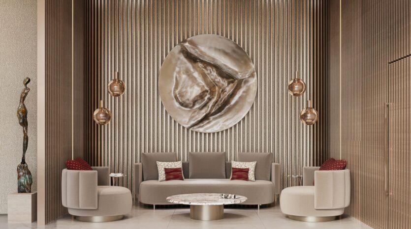 A modern living room with beige armchairs, a sofa, red accent cushions, a round Holm One marble coffee table, metal pendant lamps, and large circular abstract wall art on a textured vertical panel. A slender abstract sculpture stands to the left.