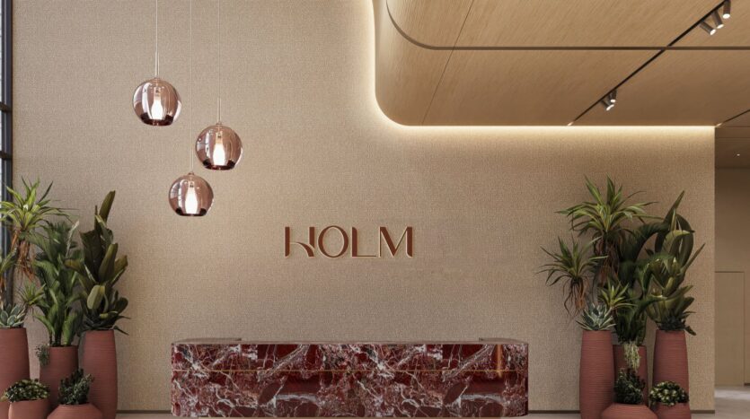 A modern entrance hall with a marble reception counter, large potted plants, three pendant lamps, and "Holm One" displayed on the wall. The space features a neutral color palette complemented by warm lighting.