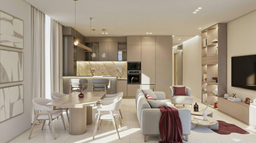 Holm One's modern, open-plan living space includes a dining area, a neutral-toned kitchen, a light gray sofa, a television, built-in shelves, and contemporary décor. Pendant lights hang above the dining table and kitchen island.