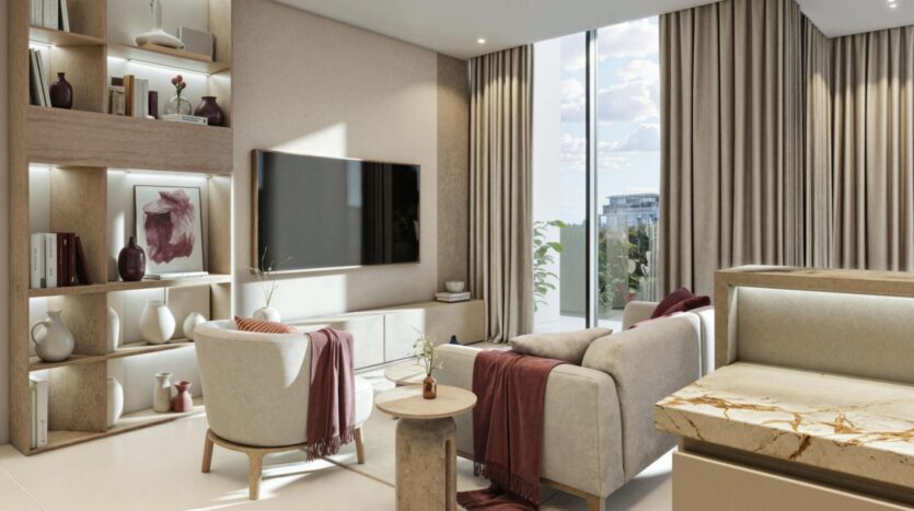 A modern living room with beige Holm One furniture, a wall-mounted TV, built-in shelves with decorative items, large windows with beige curtains, and a marble countertop in the foreground. Sunlight illuminates the space.