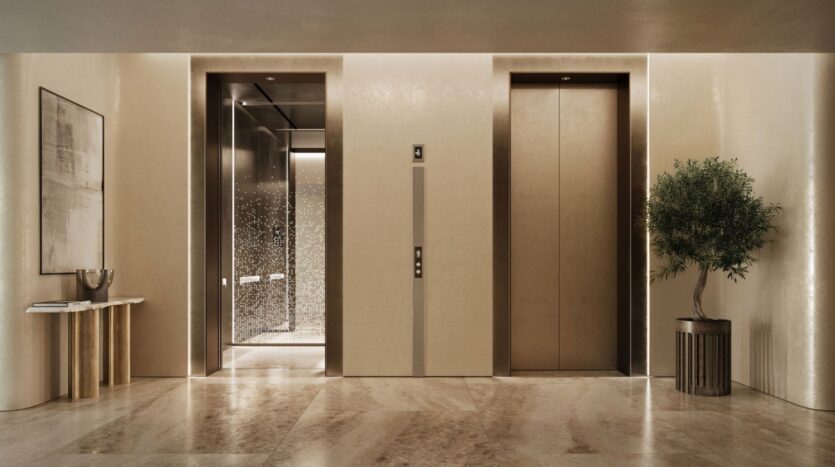 Modern and elegant entrance hall of the Lia elevator with two elevators, marble floors, beige walls, a large potted plant on the right, a console table with decorative objects on the left, and a framed abstract artwork on the wall.