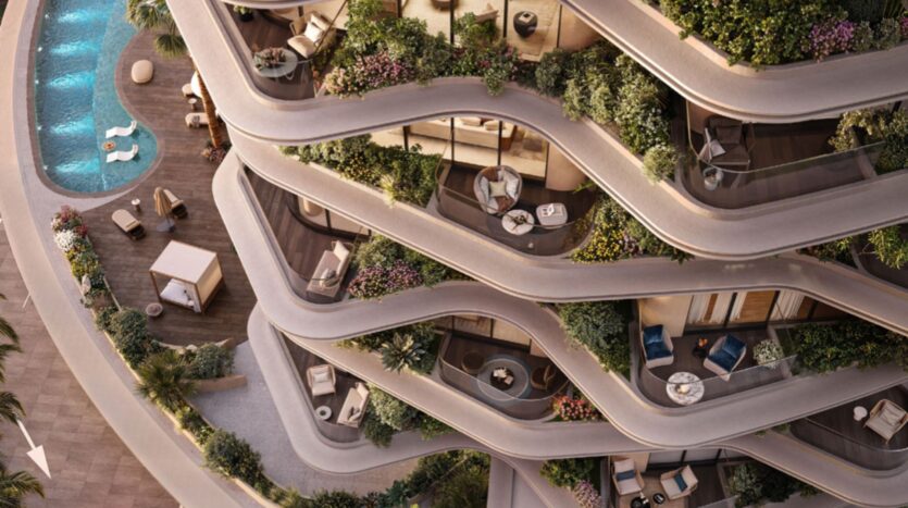 Aerial view of Lia's modern building with curved balconies filled with plants and outdoor furniture, overlooking a swimming pool and landscaped terrace below. The design is characterized by flowing lines and lush vegetation.