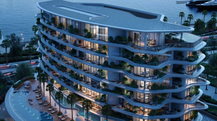 Lia's modern luxury apartment building, which spans several floors and features curved balconies, overlooks a bright swimming pool and the ocean at sunset. Illuminated and surrounded by palm trees, it offers a welcoming atmosphere, similar to that of a resort.