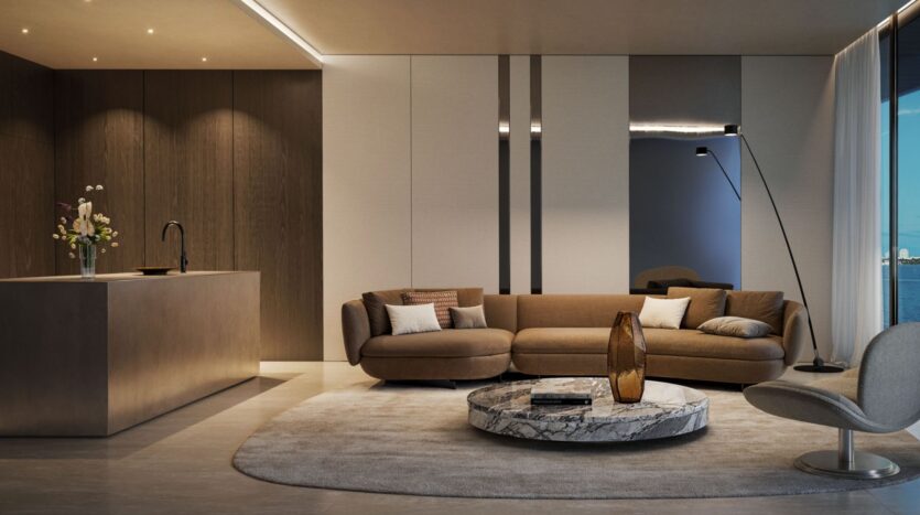 Modern living room with brown sofas, a round marble coffee table, and large windows offering views of Lia's seafront. The open-plan kitchen features a sleek island and a vase of flowers, all in a neutral color palette.
