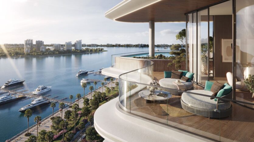 Lia's modern balcony, with its round lounge chairs, glass railings, and greenery, overlooks a marina with yachts, palm-lined walkways, and urban buildings, set against calm waters and clear skies.