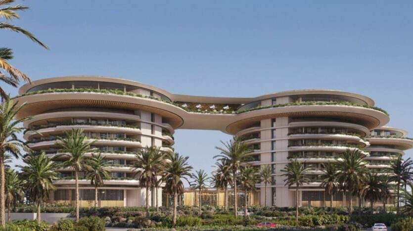 The edition consists of a modern complex of two circular buildings connected by an aerial bridge, surrounded by palm trees and lush landscaping under a clear blue sky.
