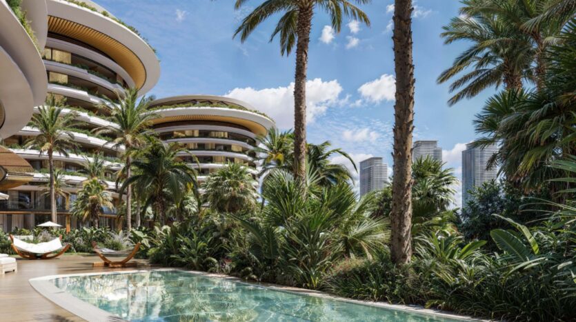 Luxury buildings, including The Edition with its curved balconies, rise behind lush tropical gardens and palm trees. A transparent swimming pool sparkles in the foreground, while the skyscrapers of the modern city stand tall under a bright blue sky.