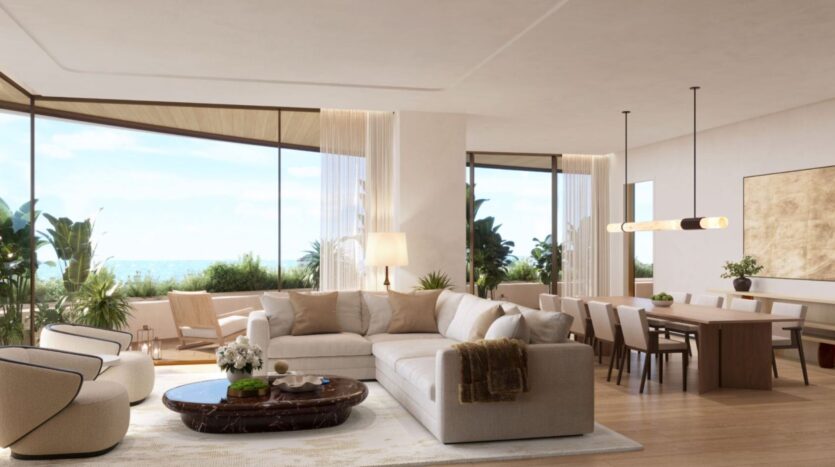 Modern living and dining room in the Edition, with neutral tones, large windows offering ocean views, contemporary furniture, indoor plants, and natural light filling the open and airy space.