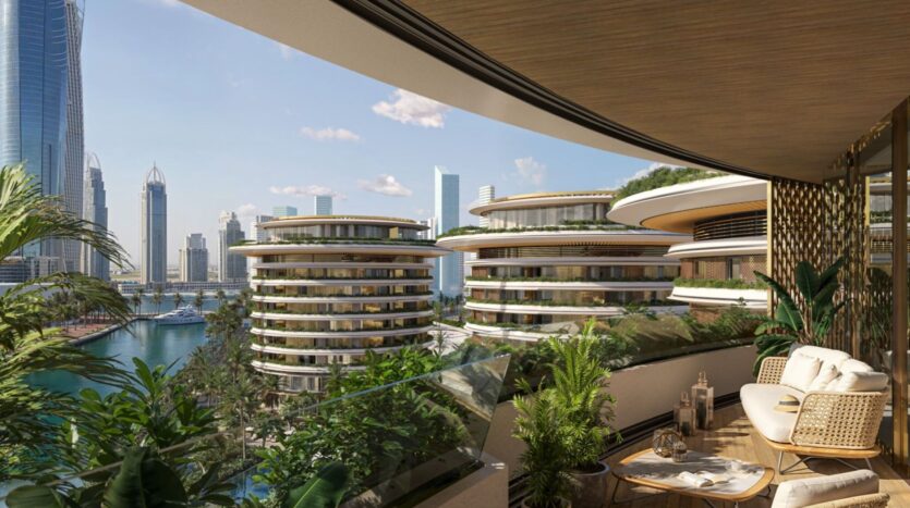 The modern balcony of the Edition, furnished with wicker chairs, a small table, and lush plants, overlooks futuristic buildings with rounded shapes and the city skyline, filled with tall skyscrapers under a blue sky.
