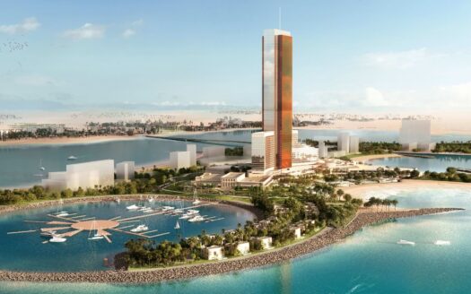 Un grand gratte-ciel moderne se dresse sur une île au bord de l'eau à Ras Al Khaimah, entouré de verdure, de quais et de bateaux - un décor qui invite à se poser la question : faut-il investir dans l'immobilier à Ras Al Khaimah ? Des plages et des vues sur le désert complètent la scène.