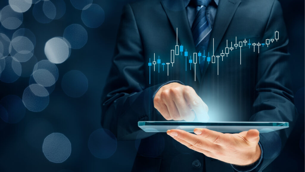 Eine Person im Anzug interagiert mit einem Tablet-PC, auf dem eine leuchtende Finanzgrafik und steigende Trendlinien angezeigt werden – symbolisch für die Datenanalyse oder das Wachstum des Aktienmarktes vor dem Hintergrund des Aufstiegs der „Besteuerung in Dubai: Warum europäische Investoren aktiv werden“.