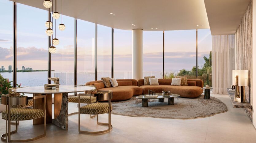 A modern and spacious Lia living room with floor-to-ceiling windows overlooking the water and city buildings, featuring a curved brown sofa, circular coffee tables, a round dining table, and elegant chairs.