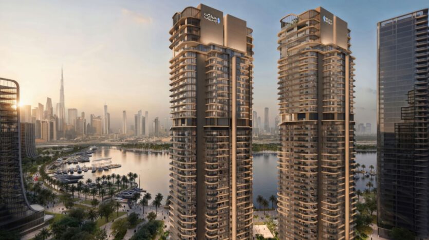 Two modern towers bearing "Creek Waters" signs showcase architectural artistry as they overlook a marina and palm-lined promenade, with the city skyline and Burj Khalifa visible in the background at sunset.