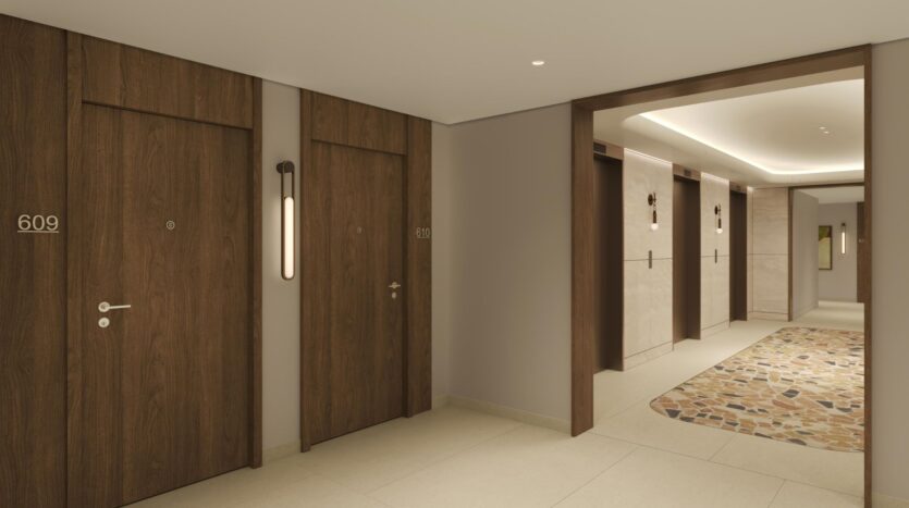 A hallway in a modern hotel with wooden doors marked 609 and 610, beige walls, patterned carpet, and recessed ceiling lighting. Three elevator doors are visible in the background, combining art with a clean and tranquil atmosphere.