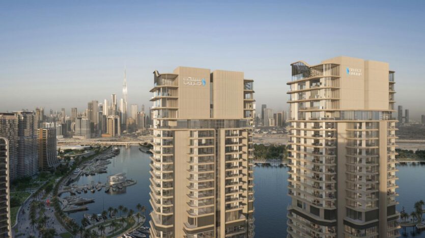 Two modern skyscrapers showcase architectural artistry as they tower over a marina dotted with boats and palm trees, while the city skyline and the iconic Burj Khalifa rise in the background under clear skies.