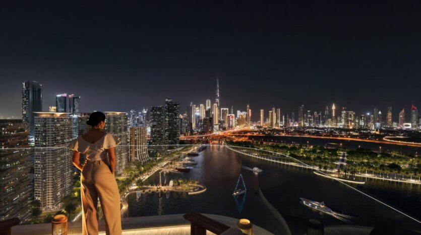 A woman stands on a rooftop terrace at night, overlooking the skyline of a modern city whose illuminated skyscrapers along the riverbank are a testament to architectural artistry. Boats sail across the water, reflecting the city's vibrant lights.