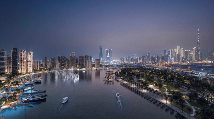 A nighttime cityscape showcases the artistry of skyscrapers, an illuminated waterfront, boats gliding along the river, and a palm-lined park. The vibrant skyline sparkles under the clear evening sky.