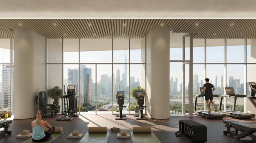 A modern gym with large windows overlooking the city skyline, where the art of fitness comes to life. People use treadmills and exercise on yoga mats in bright natural light, surrounded by neatly arranged equipment.