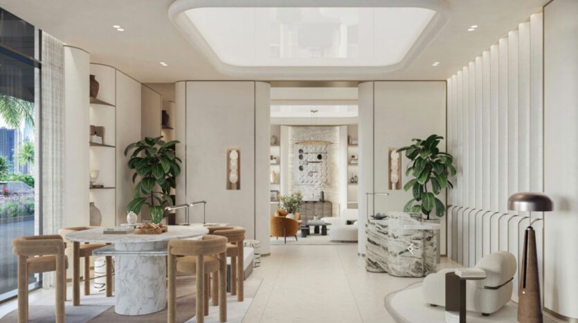 A modern and elegant room with light walls and marble accents at Eltiera Views, featuring a round table and wooden chairs, lush green plants, curved shelves, and an elegant sitting area in the background.