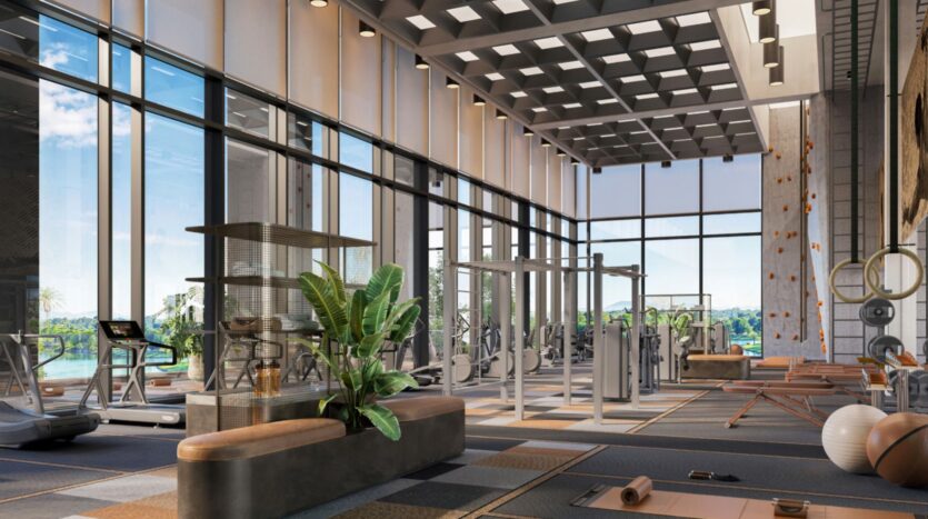 Modern gym with large floor-to-ceiling windows, various exercise equipment, yoga mats, free weights, a climbing wall, indoor plants, and panoramic views of the Eltiera in the background.
