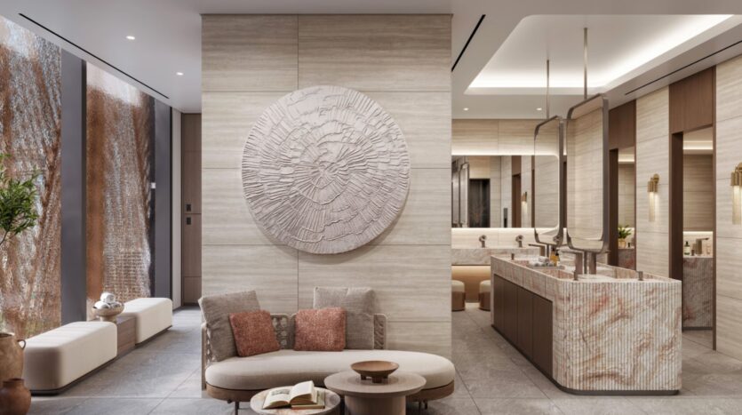 The modern and elegant living room and bathroom at Eltiera Views feature neutral tones, textured walls, a large round wall art piece, stylish seating, benches, and double vanity units; soft natural light floods the space.