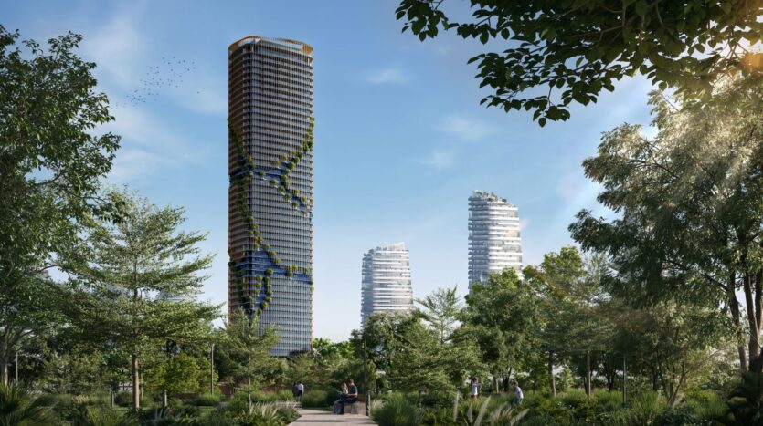 A large modern skyscraper, whose spiral structure is covered with green plants, rises near Kanyon, surrounded by lush trees and two other similar towers, under a blue sky. People are walking along a path in the foreground.