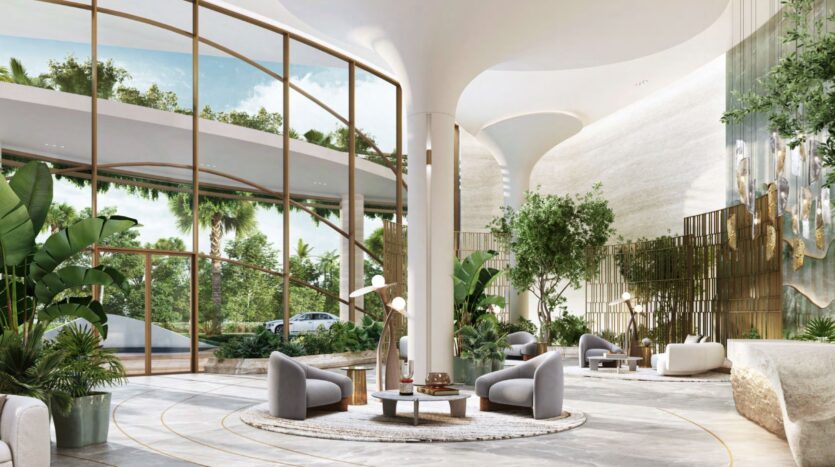 The modern and spacious lobby of the Kanyon Hotel features tall windows, lush indoor plants, curved seating, and natural light. Elegant chairs surround low tables on round rugs, while greenery and trees are visible outside.