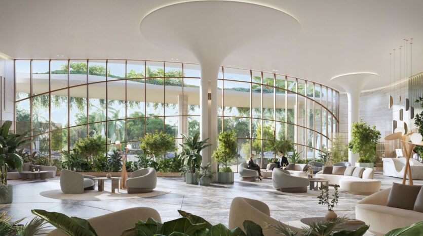 The hotel's spacious and modern lobby, with large floor-to-ceiling windows, overlooks the Kanyon, with abundant natural light, lush green plants, and contemporary seating. People sit inside while the greenery flourishes outside.