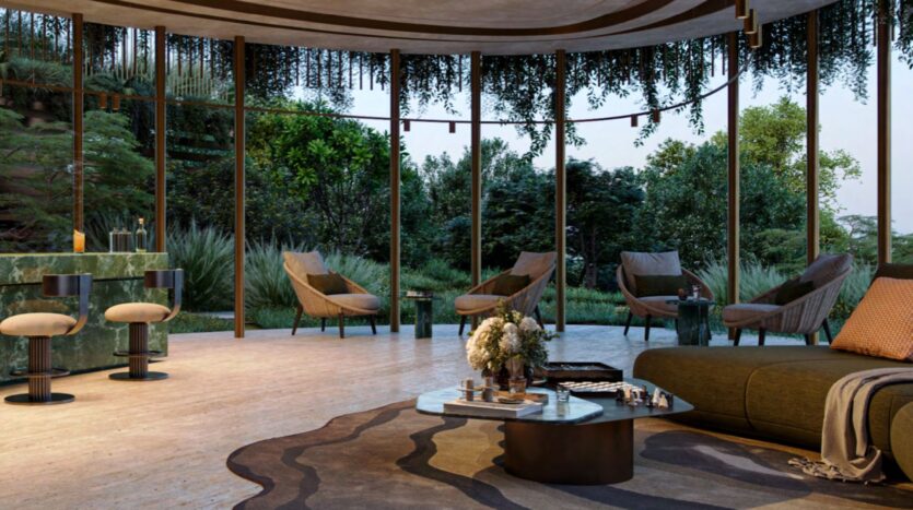 Modern living room with floor-to-ceiling windows at Kanyon, featuring contemporary chairs, a curved sofa, a marble coffee table, and lush greenery visible outside. Hanging plants and natural light create a relaxing and welcoming atmosphere.