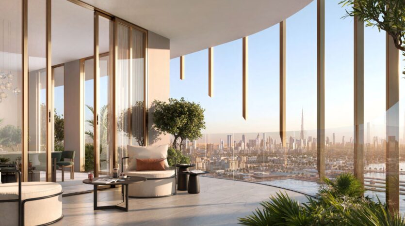 Spacious modern balcony with glass walls, stylish seating, potted plants, and panoramic views of the city at sunset. Large buildings, including the iconic Kanyon Tower, are visible in the distance.