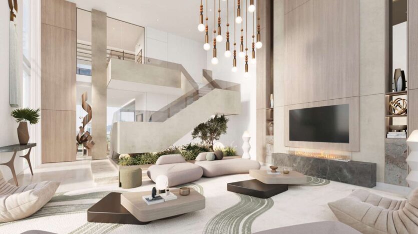 Un salon spacieux et moderne à Soto Grande avec des tons neutres, un mobilier minimaliste, un escalier central, des lampes suspendues, une télévision murale au-dessus d'une cheminée et des plantes d'intérieur en guise de décoration.