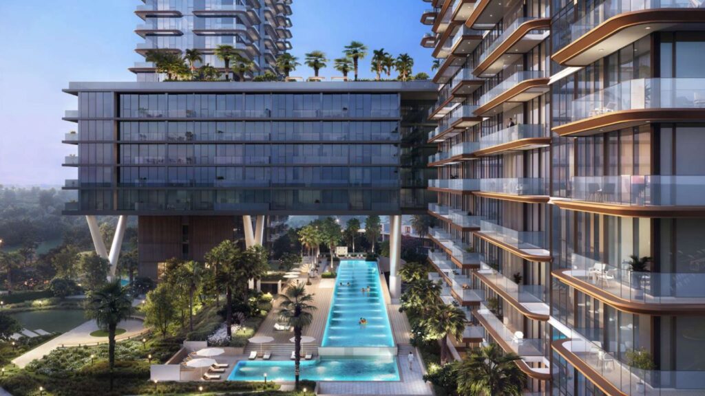 Des tours d'habitation modernes avec des balcons en verre donnent sur une longue piscine extérieure entourée de palmiers, de chaises longues et de verdure dans l'environnement urbain luxueux de Soto Grande au coucher du soleil.