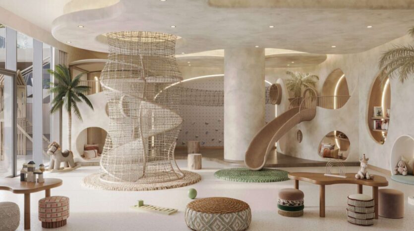 Salle de jeux intérieure moderne et spacieuse en Soto Grande avec des tons neutres, comprenant une structure d'escalade en corde spirale, un toboggan tunnel, un mur d'escalade, des fenêtres rondes et des sièges rembourrés et moelleux. Des jouets en peluche et un décor ludique complètent la scène.