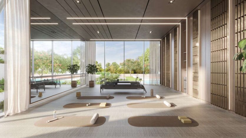 Un studio de yoga lumineux et spacieux à Soto Grande avec des fenêtres allant du sol au plafond, des tapis d'exercice, des accessoires de yoga et de la verdure à l'extérieur. La salle moderne bénéficie de la lumière naturelle et d'un décor minimaliste pour un espace de pratique serein.