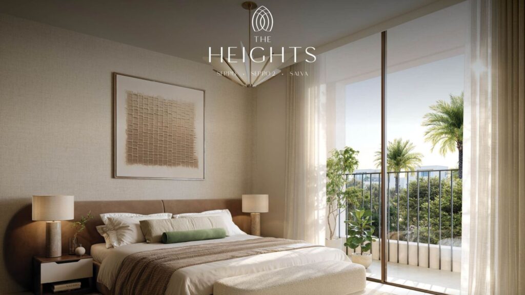 The modern room at The Heights hotel features a large bed, bedside tables, and neutral décor. Floor-to-ceiling windows open onto a balcony with palm trees and greenery. The "The Heights" logo is displayed at the top of the image.