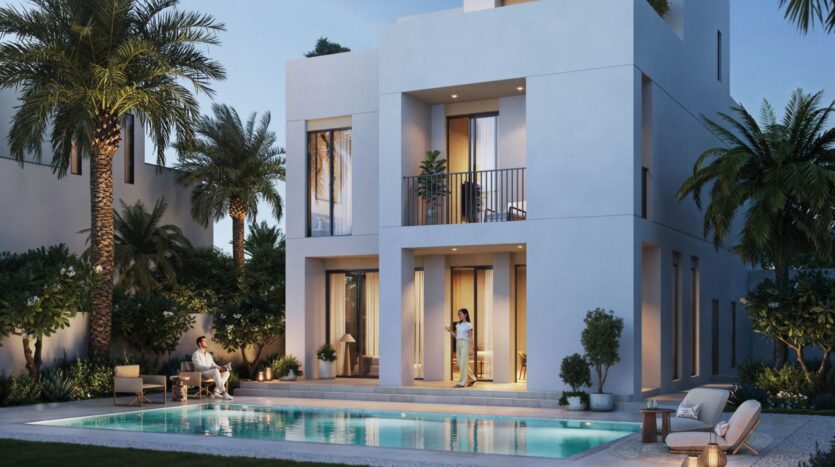 A modern two-story white house in The Heights, with large windows, surrounded by palm trees and gardens. A swimming pool is in the foreground; a woman stands on the patio and a man sits nearby, enjoying a peaceful evening outdoors.