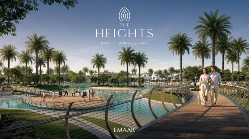 A couple walks across a curved wooden bridge over a pond surrounded by palm trees, manicured lawns, and modern villas under a clear blue sky. The text reads "The Heights"—a serene lifestyle offered by EMAAR.